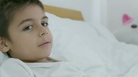 Asthma attack. Young child lying in the bed and coughs, mom gives him inhaler Stock Footage 256606959