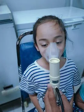 Asthma child using nebulizer in a clinic due to respiratory problem. Stock Photos