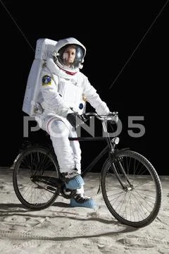 An astronaut on a bicycle on the moon Stock Photos