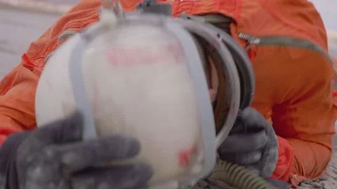 Astronaut crawling through desert terrain in bright orange overalls under blue Stock Footage 288805726