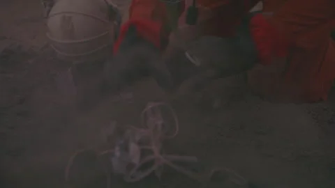 Astronaut digging dirt with gloves in a barren terrain during a scientific Stock Footage 288796342