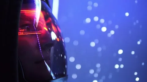 Astronaut, donning helmet with reflective visor, gazes at swirling particles in  Stock Footage 293346151