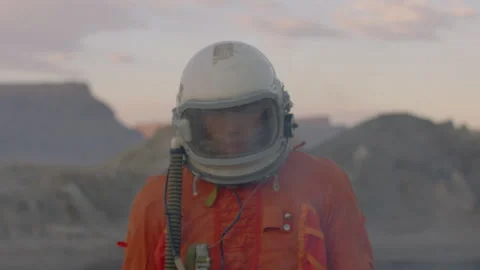 Astronaut exploring desert landscape in orange overalls and helmet Stock Footage 288698625