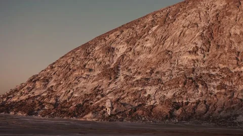 An astronaut at the foot of the hill takes the first steps towards climbing it Stock Footage 159782879