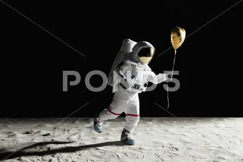 An astronaut on the moon holding a heart shaped helium balloon Stock Photos