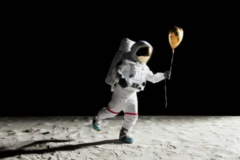 An astronaut on the moon holding a heart shaped helium balloon Stock Photos