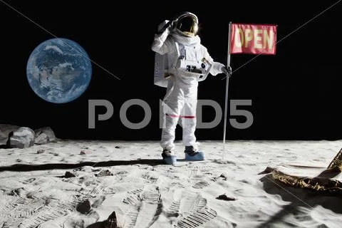 An astronaut on the moon saluting next to a flag with OPEN on it Stock Photos
