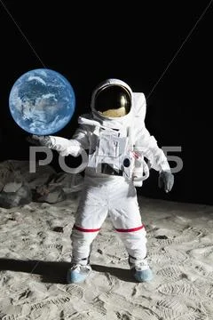 An astronaut on the moon's surface pretending to hold the earth Stock Photos