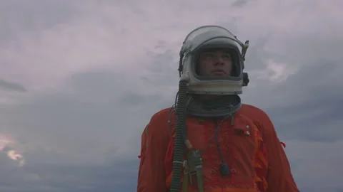 Astronaut in orange overalls explores cloudy sky during twilight hours Stock Footage 288803559