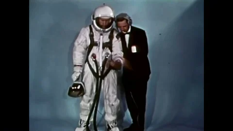 An astronaut pulling on a glove, showing his spacesuit, a handler helping him to Stock Footage 85203375