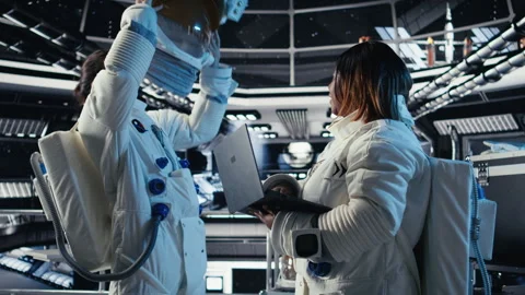Astronaut returning from planet surface takes helmet off, talking with colleague Stock Footage 311085562