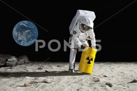 An astronaut rolling a drum of toxic material on the moon surface Stock Photos