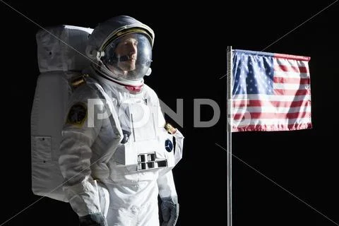 An astronaut with a serious expression standing next to an American flag Stock-Fotos
