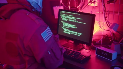 Astronaut Sits Typing Code on Computer in Surveillance Room Stock Footage 270333678
