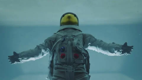 Astronaut spreading arms and falling back into the light below at zero gravity 스톡 동영상 219928421