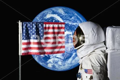 An astronaut standing by an American flag with the earth in the background Stock Photos
