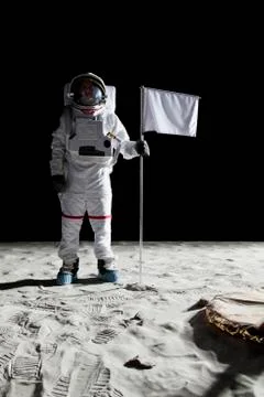 An astronaut standing next to a white flag Stock Photos