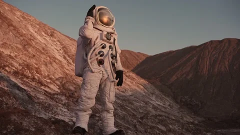 Astronaut standing on a rock opens the flap of his helmet and looks around Video stock 159664394