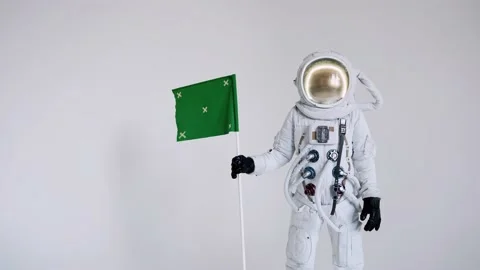 Astronaut stands with a flag on a light background. studio Stock Footage 159665764