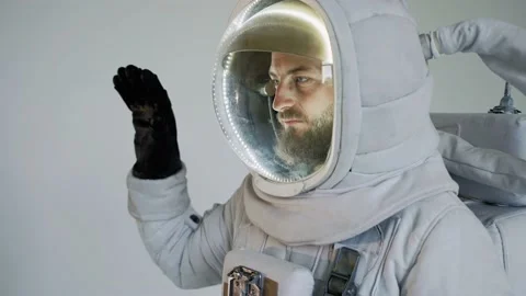 Astronaut stands with on a light background and waves his hand. studio Vídeo Stock 159664512