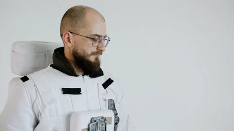 Astronaut stands on a light background with a serious expression on his face Video stock 159663215