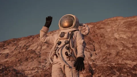 Astronaut stands on a rock waving his hand against the sky. discovery new planet Stock Footage 159664053