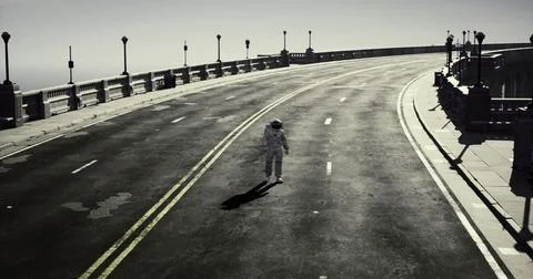 Astronaut walking alone on an empty road alongside the ocean in daylight Illustrazione stock