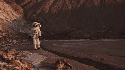 The astronaut walks cautiously along the stream, raises his hand. Video stock 159669077