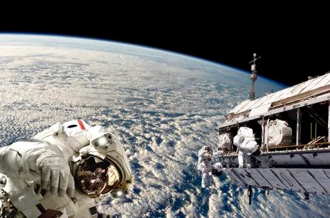 Astronauts performing work on a space station while orbiting Earth. Foto stock