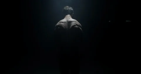 Atheletic Male With His Back To The Camera In A Dark Background Lifting Weights Stock Footage 113787886