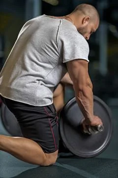 Athlete adding weight plates on his barbell Stock Photos