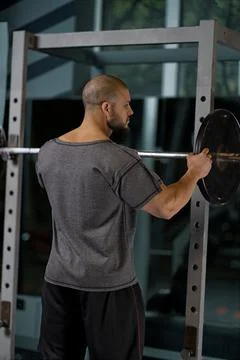Athlete adding weight plates on his barbell Stock Photos