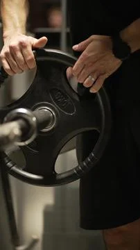 An athlete adds weight to the exercise machine in the gym Stock Photos