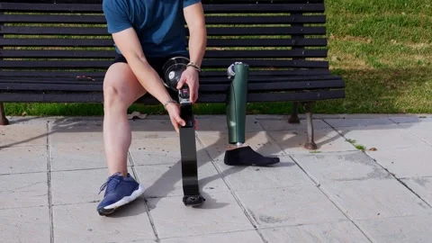 Athlete Adjusting High-Tech Prosthetic Leg for Outdoor Exercise Stock-Footage 264035494