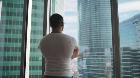 Athlete on the background of window windows. Athletic man looking out the win Stock Photos
