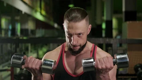 Athlete with a beard trains and does biceps exercises with dumbbells in the gym Stock Footage 234326420