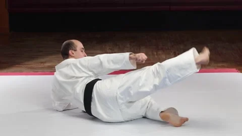An athlete with a black belt performs kicks while lying on the surface Stock Footage 272309824