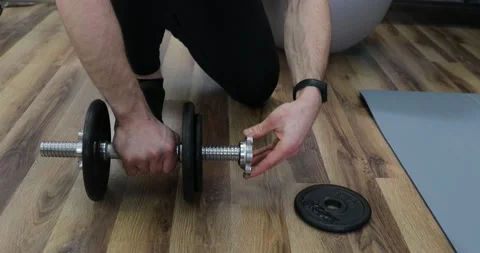 Athlete changing weights on barbell. Man Unscrews Dumbbell to Change its Weig Stock Footage 152835582