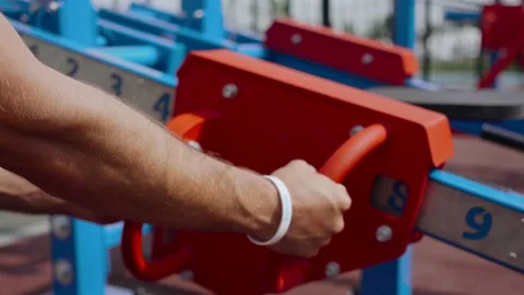 The athlete chooses the optimal weight on the simulator. Outdoor sports ground Stock Footage 135201126