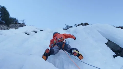 An athlete climbs an icefall with ice axes and crampons in the Alps, Switzerland Stock Footage 240158784