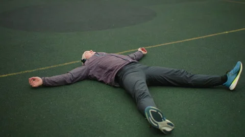 Athlete collapses outdoors, Runner rests after effort, Exhausted athlete sprawls Stock Footage 329458004