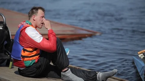 The athlete is disabled sitting on the dock and wearing sneakers after training Stock-Footage 112239272