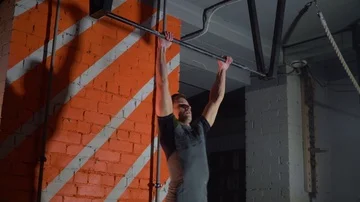 The athlete does pull-ups with a direct grip on a horizontal bar in the gym Vídeo Stock 86080933