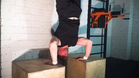 The athlete does push-ups on two cubes leaning against the wall Stock Footage 86080149