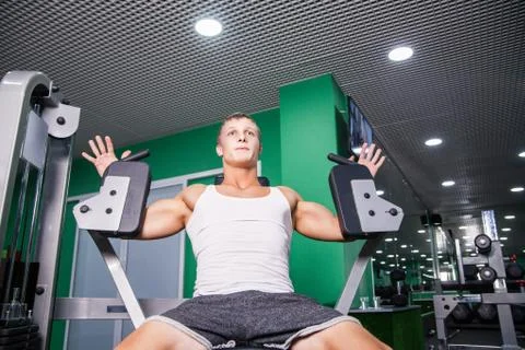 Athlete doing chest exercise on machine in gym Stock Photos