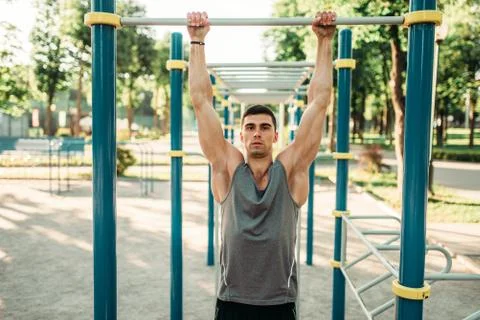 Athlete doing exercise on horizontal bar outdoor Stock-Fotos