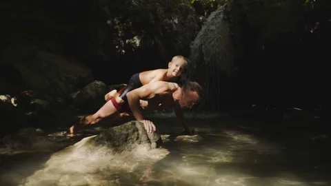 Athlete doing exercise, standing in a beautiful mountain waterfall. Bright Stock Footage 94937793