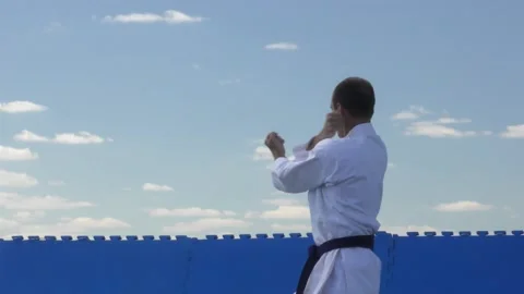 Athlete doing formal karate exercises on a background of blue sky with clouds Stock Footage 142328177