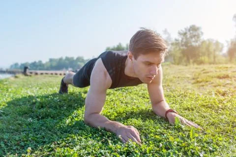 Athlete doing a plank exercise on sunny day Stock Photos