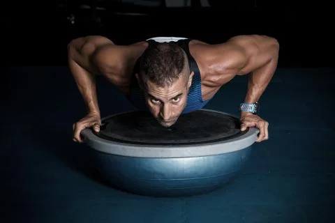 Athlete doing push-ups on balancing ball Stock Photos